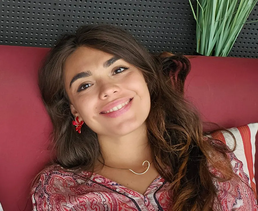 Paula, smiling, relaxing on a red sofa